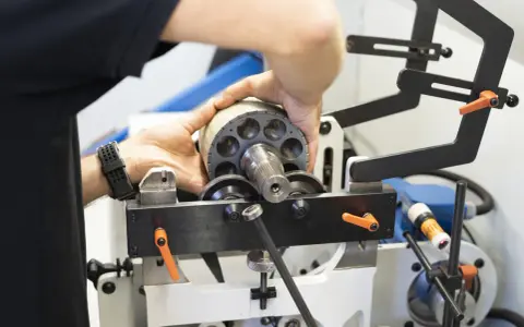 Ręce montują element wirnika pompy hydraulicznej, który jest częścią układu elektrycznego.