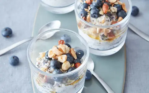 Två glas med overnight oats, toppade med blåbär, nötter och honung. Perfekt frukost!