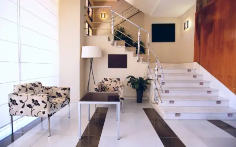 Elegante rellano escalera decoracion con sillones florales y una lámpara de pie. El descansillo escalera cuenta con una barandilla metálica y luces integradas.