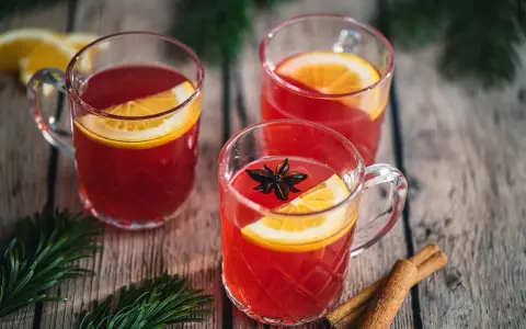Drei Tassen Kinderpunsch mit Orangenscheiben und Sternanis. Die ideale Temperatur für den Punsch ist warm und einladend.