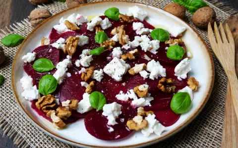 Ein Teller mit traditionellem Rote Bete Salat, garniert mit Feta, Walnüssen und Basilikum.