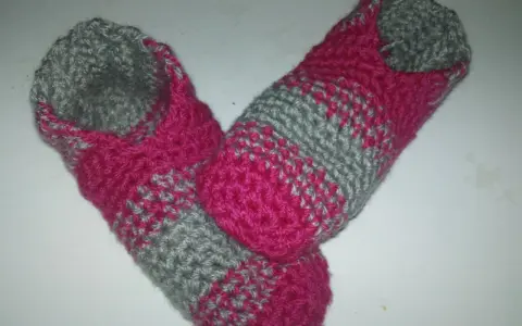 Ett par handvirkade tofflor i rosa och grått. Perfekta för mysiga hemmakvällar.
