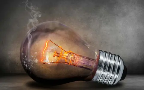En glödlampa med glödande tråd och rök som stiger från en spricka. Kanske en symbol för högt elpris nattetid.