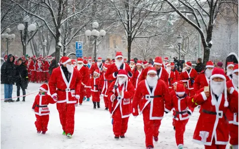 En stor grupp tomtar, både vuxna och barn, deltar i en snöig santa run.