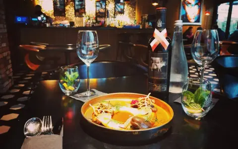 Elegancka kolacja w Nowym Targu. Na stole danie, wino i woda. Idealne miejsce, by dowiedzieć się, gdzie zjeść w Nowym Targu.