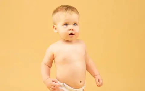 Małe dziecko w pieluszce, z zaciekawieniem patrzy w bok. Czy to stulejka, co to?