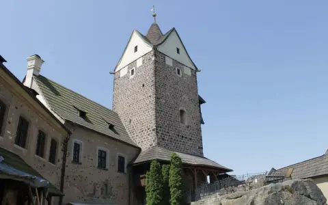 Kamienny zamek Loket z wieżą i budynkami mieszkalnymi pod błękitnym niebem.