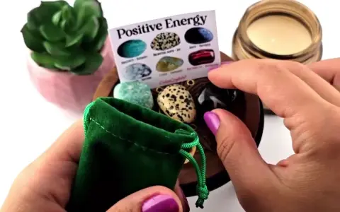 Manos sostienen una bolsa verde con piedras de energía positiva. Un folleto muestra varias piedras.