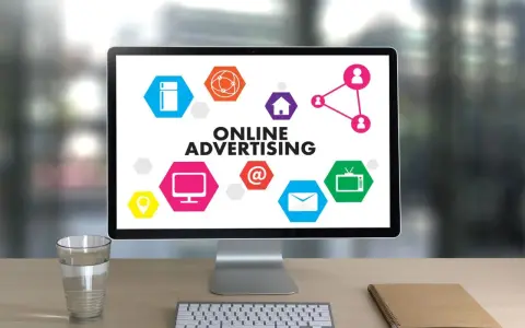 Komputer z hasłem "ONLINE ADVERTISING" i ikonami symbolizującymi różne formy reklamy online. Ciekawa reklama!