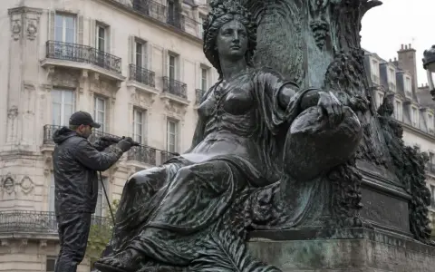 Un homme nettoie une statue en bronze avec un jet d'eau. Il apprend comment nettoyer le bronze pour redonner son éclat à l'œuvre.