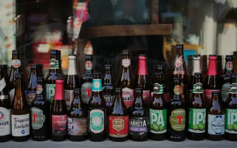 Rząd butelek z piwem kraftowym, w tym Trappistes Rochefort, Chimay, Goose Island i inne. Idealne na pytanie: jakie piwo kraftowe wybrać?