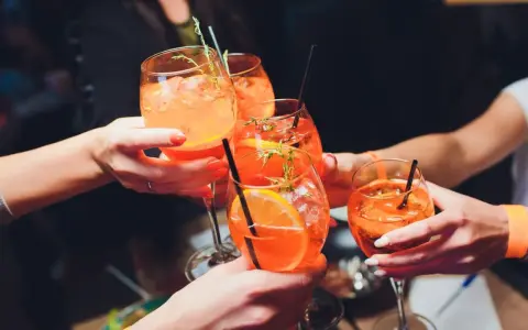 Hände stoßen mit Aperol Spritz an. So einfach wie man ihn macht, so erfrischend ist er!