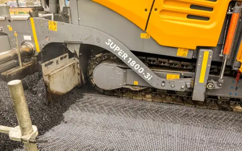 Asfaltarka w akcji, układająca nawierzchnię drogową.