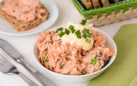 Pyszna pasta z pstrąga wędzonego, udekorowana majonezem i szczypiorkiem, gotowa do podania na chlebie.