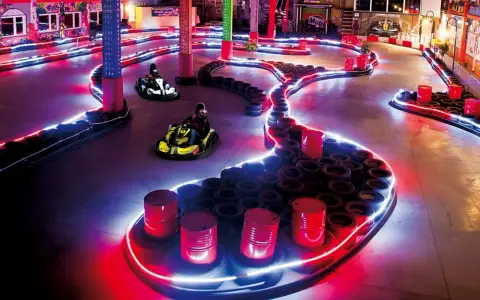 Tor kartingowy w stylu Canpol Wonderland, oświetlony neonami, z gokartami w akcji.