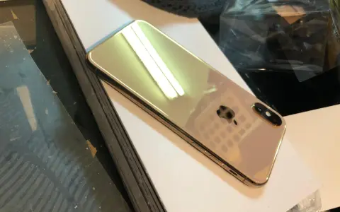 Błyszczący, złoty iPhone X leży na białej powierzchni.