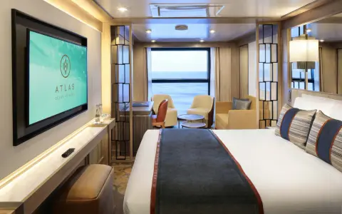 Interni lussuosi di una cabina garantita Costa Crociere con letto comodo, divanetti, scrivania e TV. Vista mare dalla finestra.