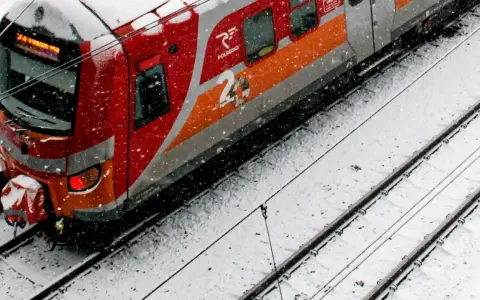 Czerwono-szary pociąg Polregio na zaśnieżonych torach.