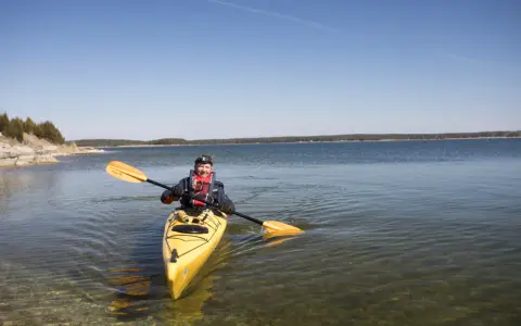 Man paddlar kanot på Gotland i klart vatten.