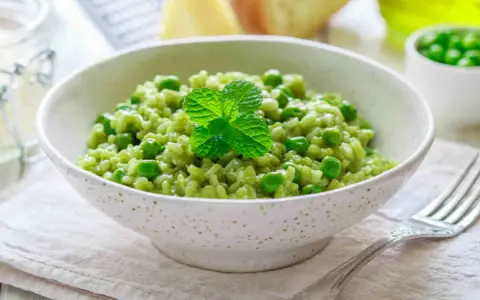 Un cremoso risotto con piselli, guarnito con menta fresca. Un piatto primaverile che celebra il gusto del riso e piselli.