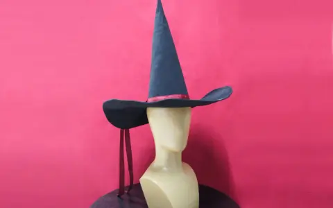Un mannequin porte un patron chapeau pointu bleu foncé avec un ruban rouge. Deux rubans rouges pendent de chaque côté.
