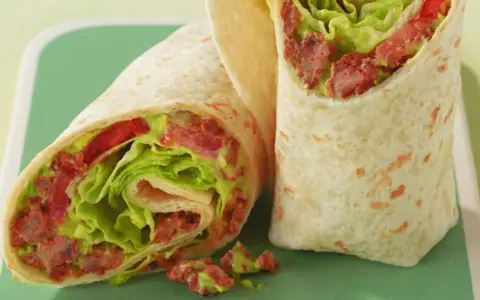 Zwei saftige wraps zum mitnehmen, gefüllt mit knackigem Salat, Tomaten und einer würzigen Fleischfüllung. Perfekt für unterwegs!