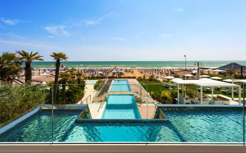Lido di Jesolo atrakcje: baseny z widokiem na plażę, palmy i morze. Idealne miejsce na wakacje.