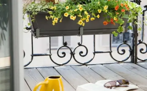 Jardinière extérieure fleurie sur un balcon, une belle idée composition pour un coin lecture avec un livre et des lunettes.