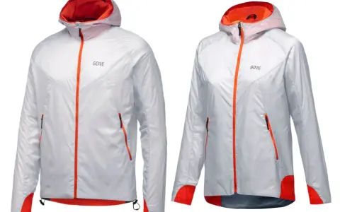 Zwei leichte, weiße Laufjacken mit orangefarbenen Reißverschlüssen und Akzenten. Perfekt für jedes Wetter dank GORE-TEX INFINIUM.