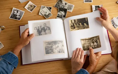 Manos hojeando un álbum de fotos antiguas, reviviendo recuerdos. Quizás buscando frases 50 aniversario para acompañar estas imágenes.