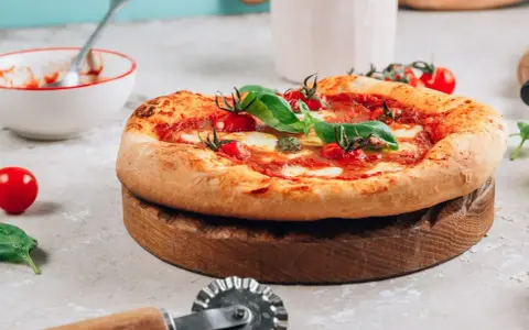 Pyszna pizza na drewnianej desce, gotowa do pokrojenia. Idealna na to, na czym piec pizze.