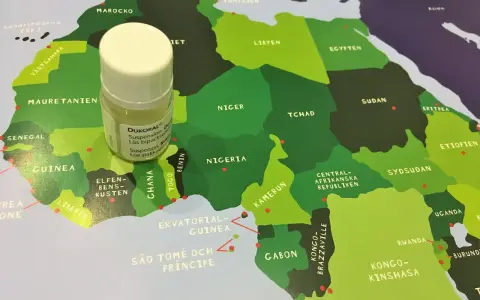 En liten flaska Dukoral® står på en karta över Afrika, nära Guinea och Elfenbenskusten.