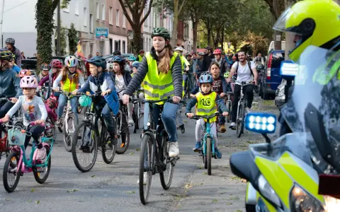 Kinder und Erwachsene radeln bei der Kidical Mass Dortmund. Viele tragen Warnwesten und Helme.