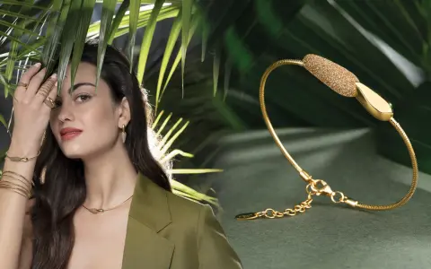 Modella con gioielli Pesavento, tra cui una collana, orecchini e anelli, su sfondo verde con foglie tropicali.