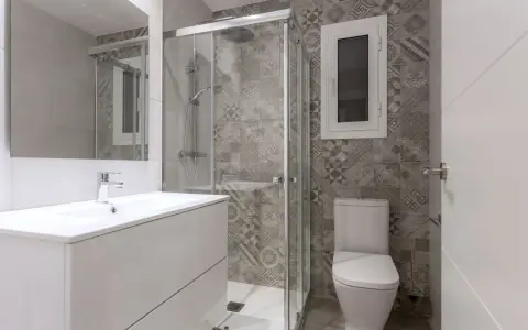 Salle de bain moderne avec douche vitrée, lavabo suspendu et carrelage graphique. Un projet pour agrandir salle de bain avec style.