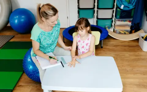 Terapeuta ocenia reakcje dziecka podczas badania sensorycznego, sprawdzając jego wrażliwość dotykową i propriocepcję.