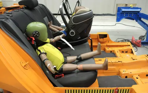 Maniquíes en un asiento de coche de prueba, preparándose para un test de seguridad según la normativa ECE R44/04.