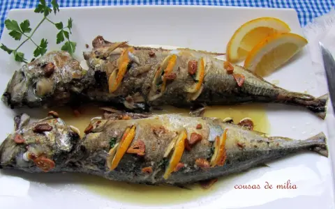 Dos jureles al horno, dorados y jugosos, con rodajas de limón y ajo. Un plato sencillo y delicioso.