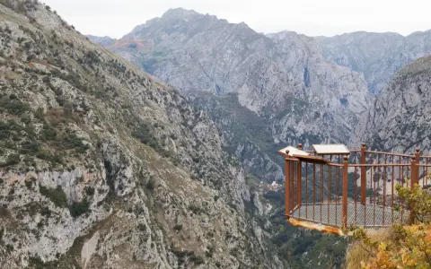 Mirador en la ruta del desfiladero de la Hermida, con imponentes montañas y un balcón de metal oxidado.