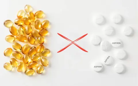 Żółte kapsułki po lewej, czerwony znak "X" na środku, białe tabletki z napisem "ASPIRIN" po prawej.