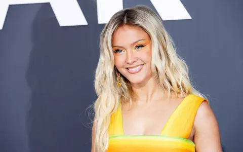 Zara Larsson ler glatt i en färgglad klänning, hennes framgångar som artist bidrar till hennes imponerande zara larsson net worth.