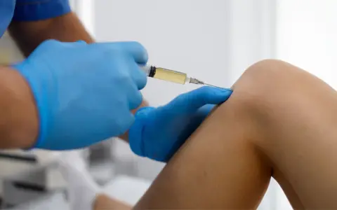 Arzt gibt Arthrose Spritze ins Knie.