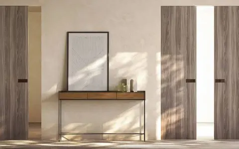 Porta in cartongesso con finitura in legno, minimalista e moderna, con un quadro astratto appeso sopra un tavolino.