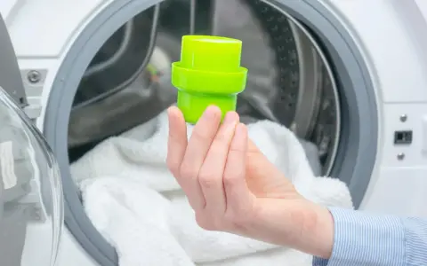 Grüne Kappe mit Waschmittel wird in die Waschmaschine gegeben.
