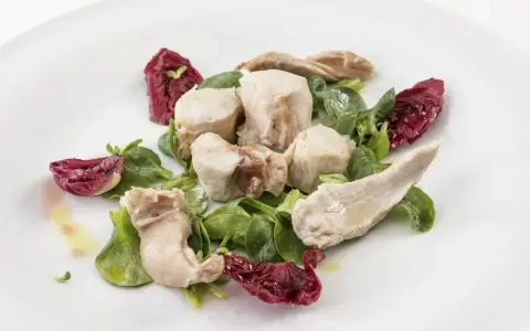 Delicato tonno di coniglio servito con insalata fresca e radicchio croccante, condito con olio d'oliva.