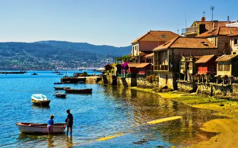Un pueblo costero gallego, con barcas en el agua y casas de piedra, uno de los pueblos mas bonitos de Galicia.