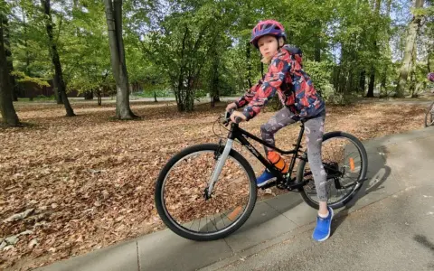Dziewczynka na rowerze, idealny rozmiar roweru dla 10 latka. Jesienny park, liście na ziemi.