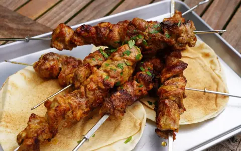 Saftige Schaschlik-Spieße, perfekt gegrillt, liegen auf Fladenbrot. Ein Genuss, der an ein gemütliches Essen im Dutch Oven erinnert.