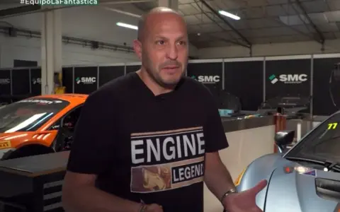 Fernando Navarrete, piloto, habla en un taller con autos de carrera.