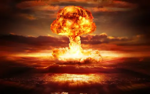 Potężny grzyb atomowy nad oceanem. Widoczne przerażające skutki bomby jądrowej: fala uderzeniowa, ogień i dym.